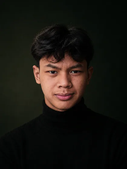 Close-up portrait of Juansyah Nursedam in a black turtleneck against an olive background.