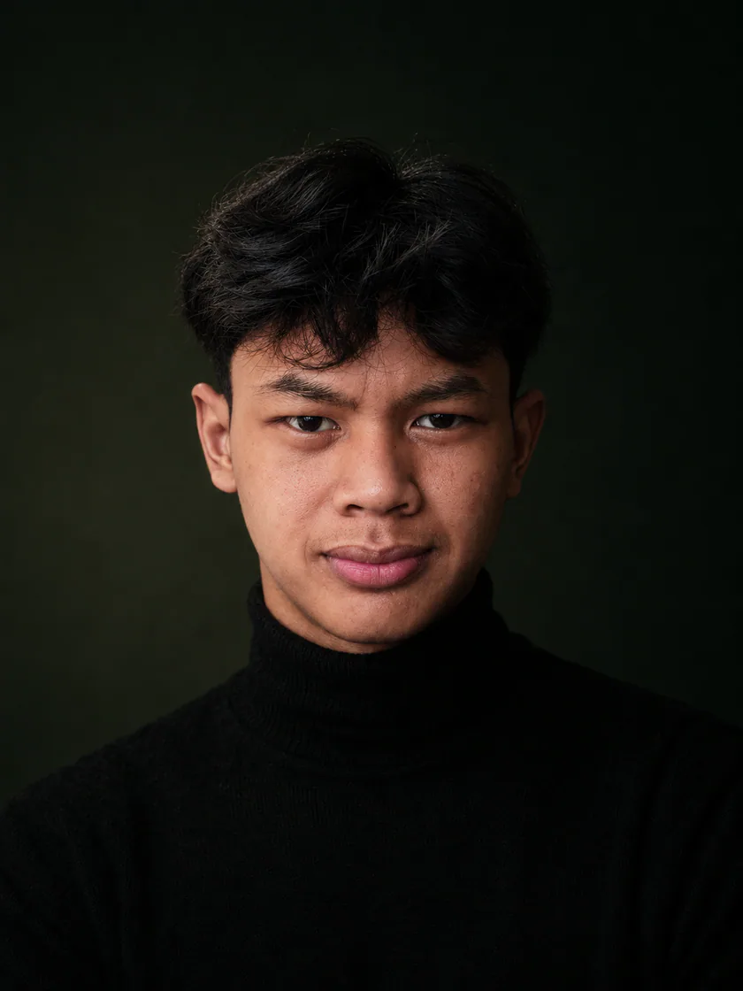 Close-up portrait of Juansyah Nursedam in a black turtleneck against an olive background.